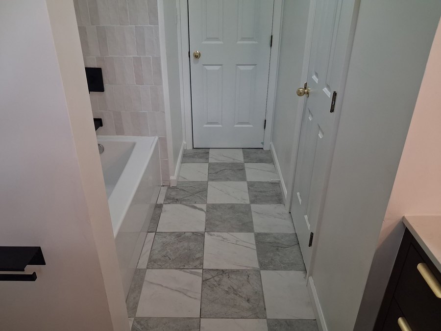 Gray and white square tile flooring beside a bathtub and white doors