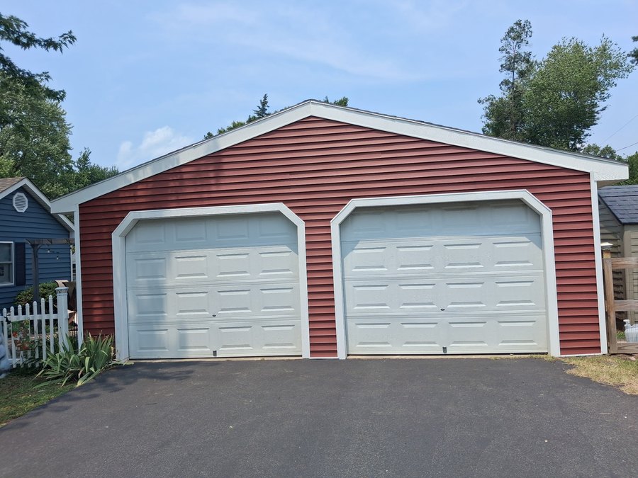Red horizontal siding with white trim around two garage doors