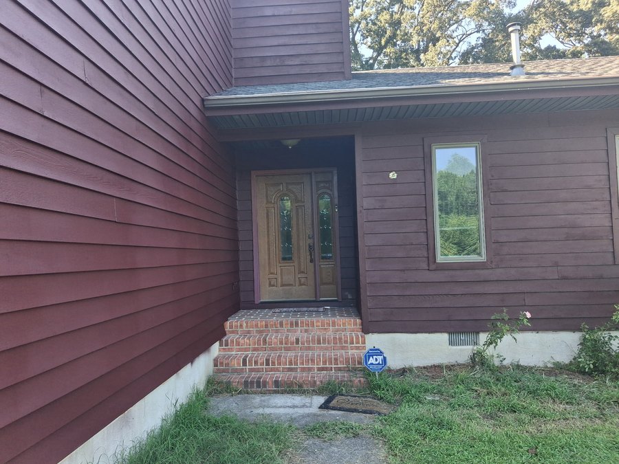Burgundy house siding around a front entry with brick steps