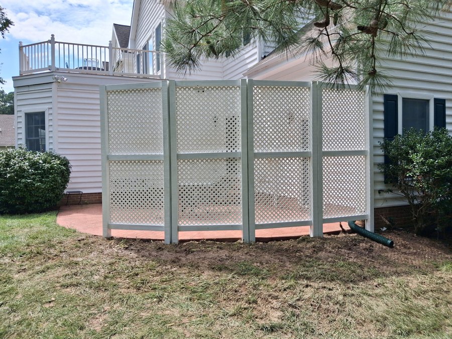 White lattice privacy screen around a patio beside a house