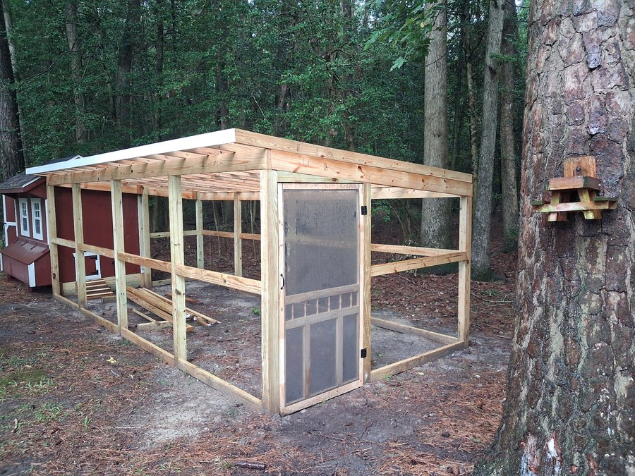 Wood framed outdoor enclosure with a framed roof and screen door during construction